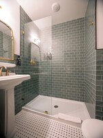 Un baño con cabina de ducha de vidrio, un lavabo blanco y un inodoro.