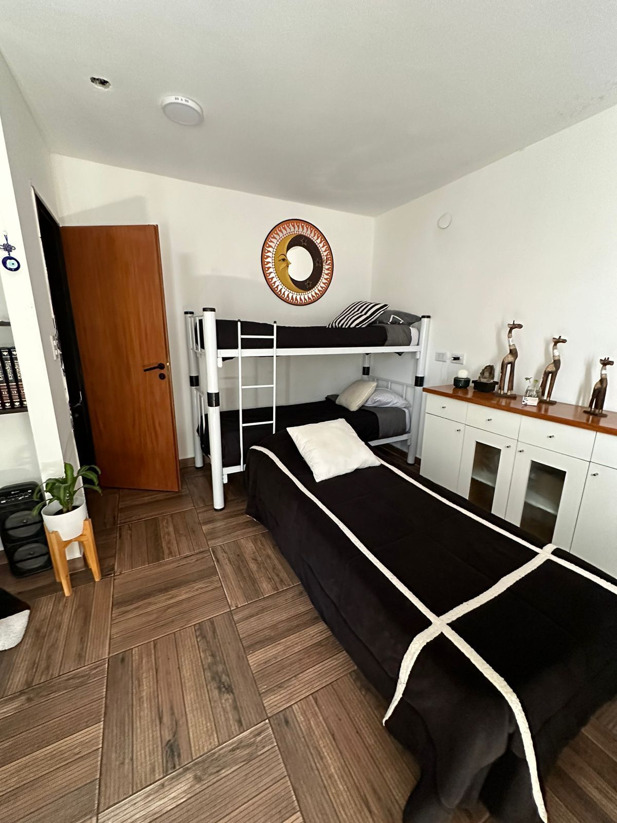 A dormitory room with bunk beds, a small kitchenette, and a wooden door.