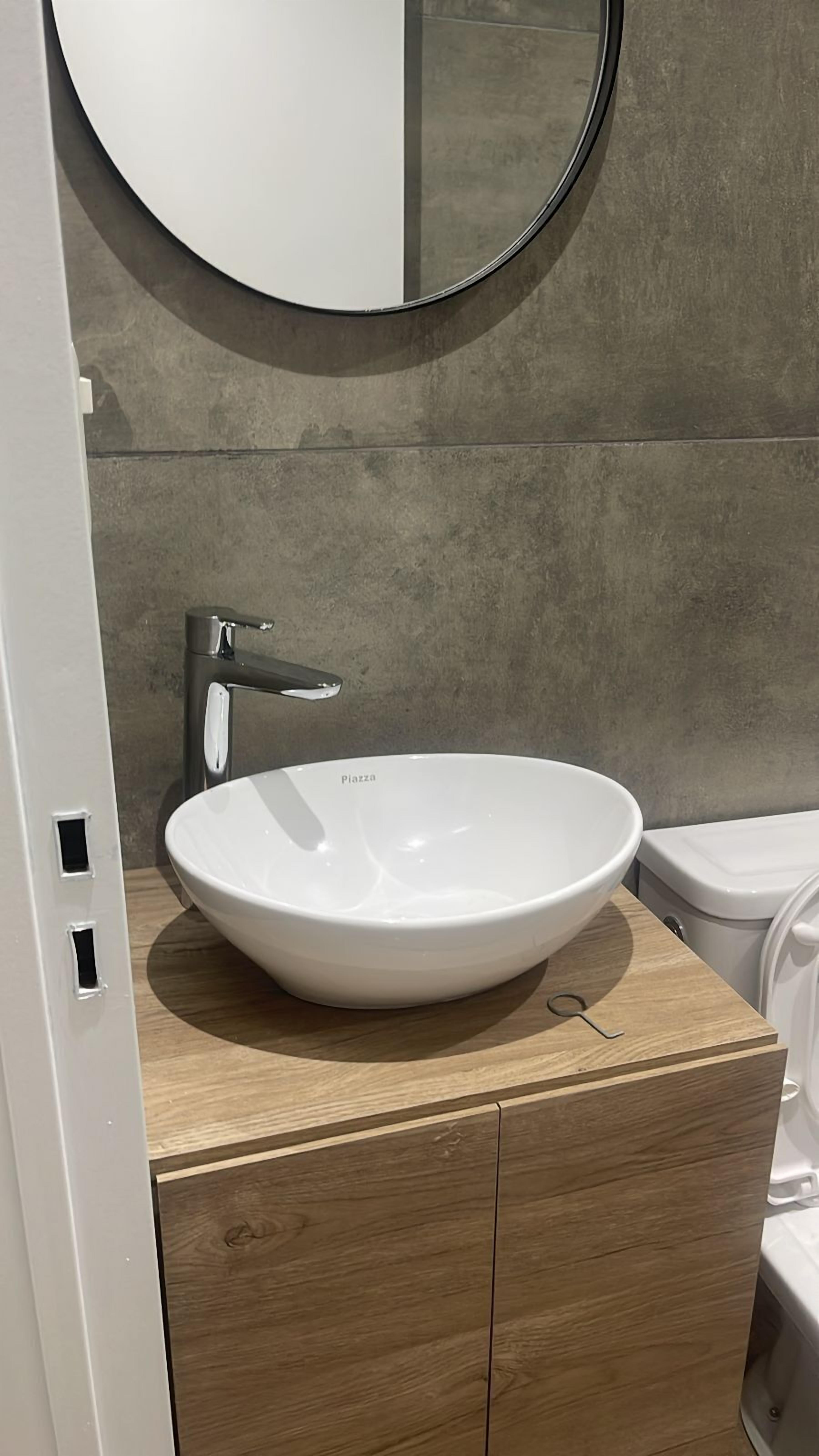 A bathroom with a white sink, a round mirror, and a toilet.