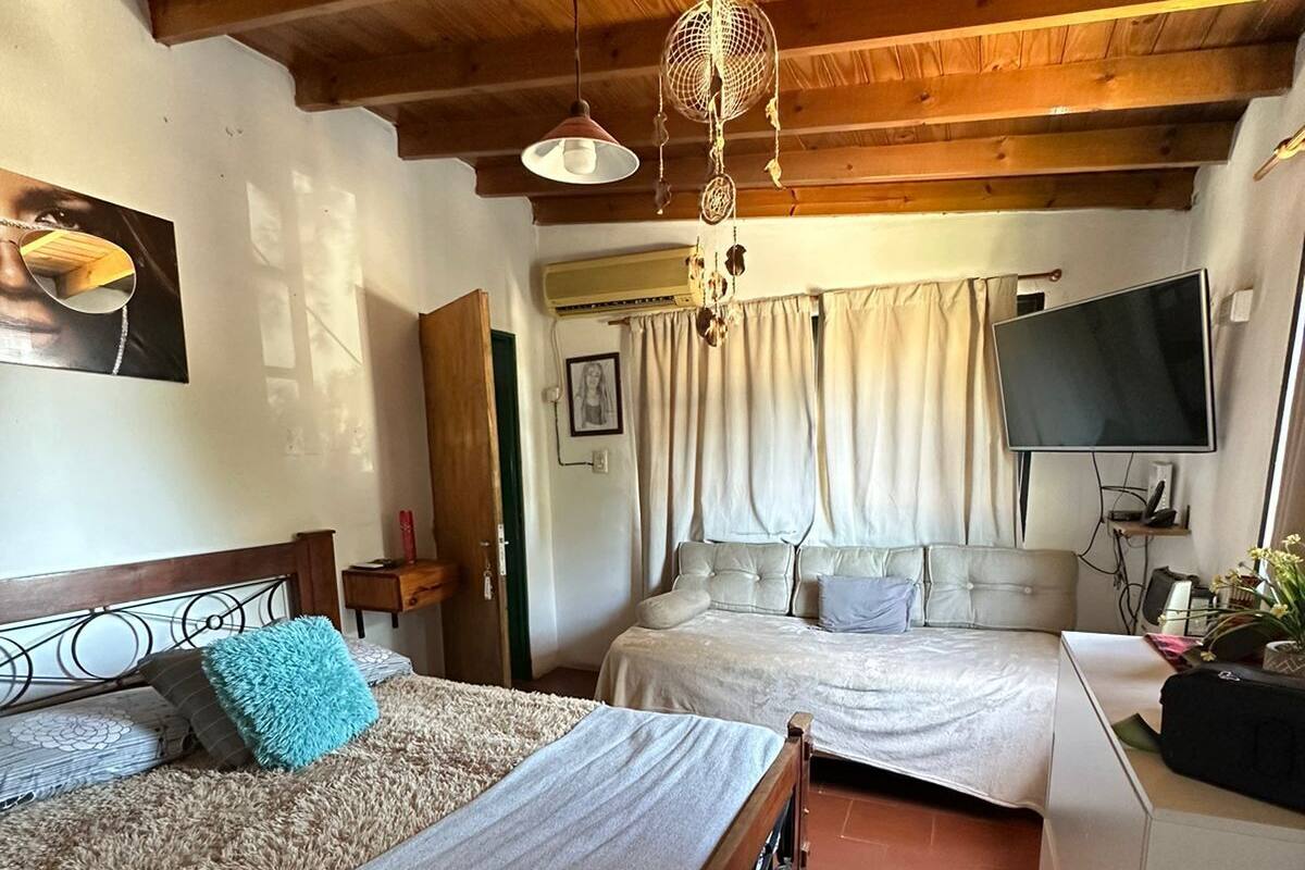 A cozy bedroom with two beds, a TV, and a wooden ceiling.