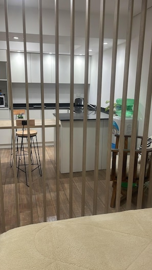 A modern kitchen with white cabinets, a central island, and a bar stool. - Anas inn (Ezeiza)