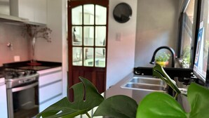 A modern kitchen with a large island, stainless steel appliances, and a view of the street outside. - Anas inn (Ezeiza)