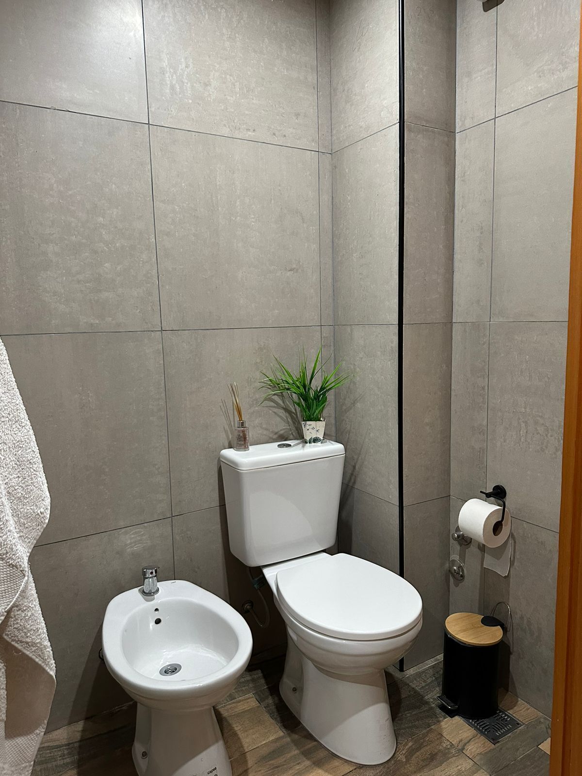 Une petite salle de bain moderne équipée de toilettes, d’un bidet et d’une petite poubelle.
