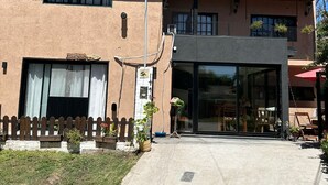 A two-story building with a modern entrance, a small porch area, and a visible balcony. - Anas inn (Ezeiza)