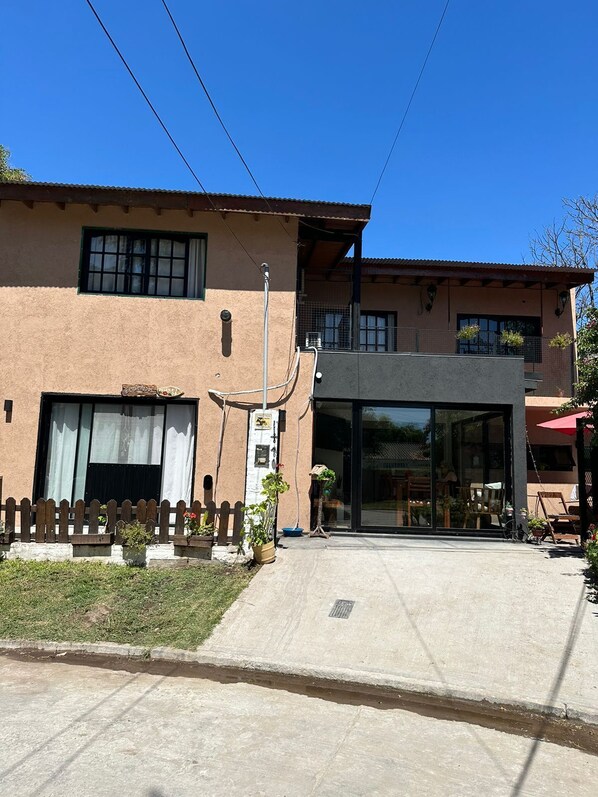 A two-story building with a modern entrance, a small porch area, and a visible balcony. - Anas inn (Ezeiza)