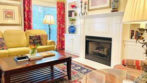 A living room with a yellow sofa, a wooden coffee table, a fireplace, and a patterned rug. - The Betty, 3BR Classic Home by Velvet Ditch Villas (Oxford)