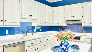 A kitchen with white cabinets, a blue backsplash, and a white countertop. - The Betty, 3BR Classic Home by Velvet Ditch Villas (Oxford)
