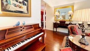 A living room with a grand piano, a painting, a mirror, and a lamp. - The Betty, 3BR Classic Home by Velvet Ditch Villas (Oxford)