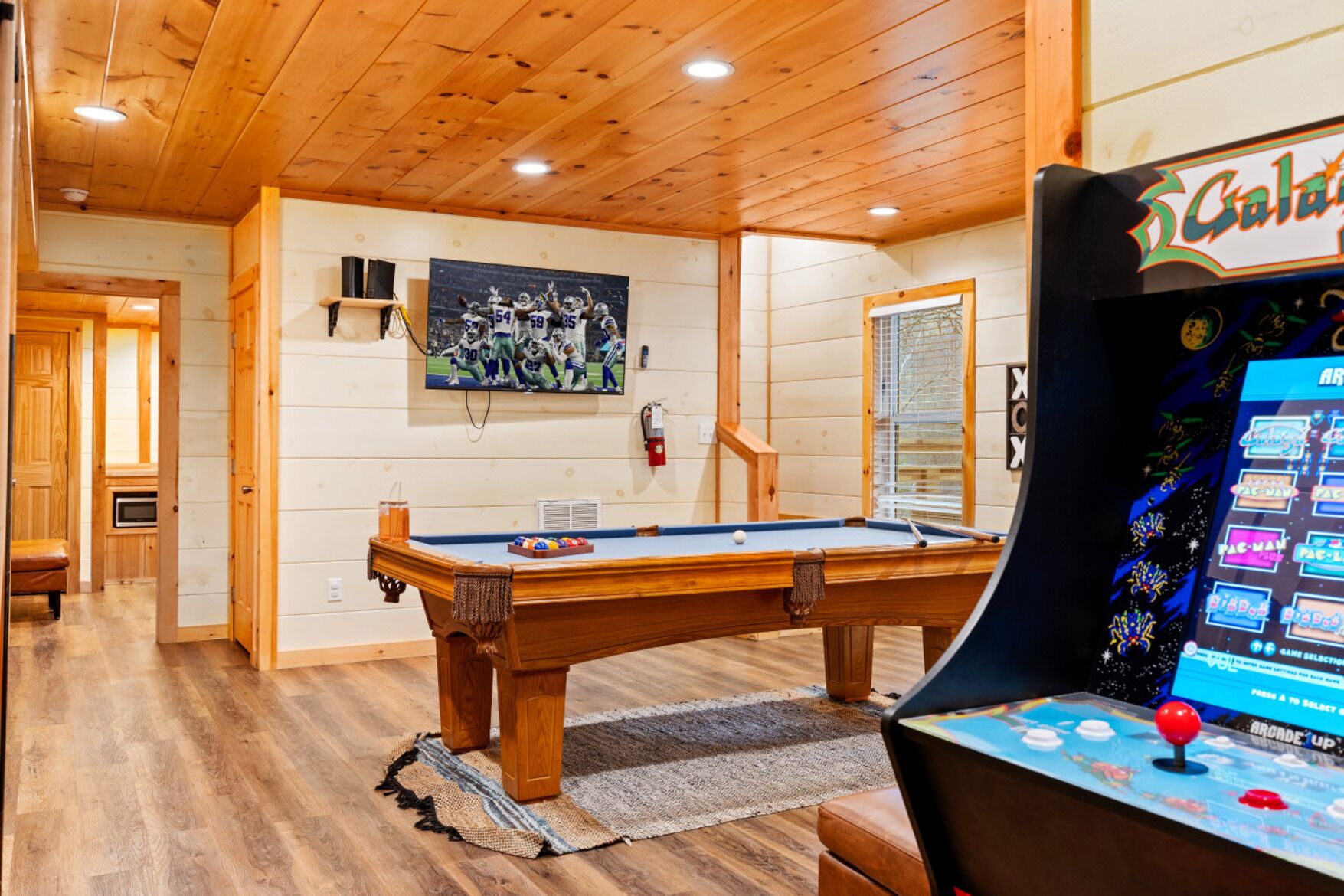 A pool table in a room with wooden walls and a ceiling.