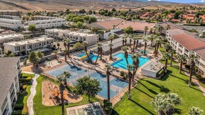 A resort with multiple swimming pools, palm trees, and a mountainous backdrop. - Modern Resort Condo - Pools, Courts & Scenic Views (St. George)