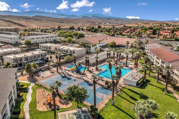 Ein Resort mit mehreren Schwimmbecken, Palmen und einer Bergkulisse.