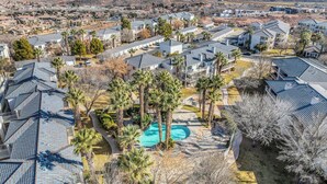 A residential area with multiple houses, a swimming pool, and a mountainous backdrop. - Modern Resort Condo - Pools, Courts & Scenic Views (St. George)