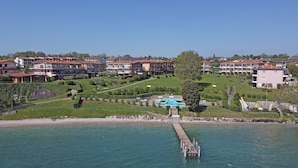 A coastal resort with a swimming pool, a pier, and multiple residential buildings. - San Sivino 142 Apartment by Wonderful Italy (Manerba del Garda)