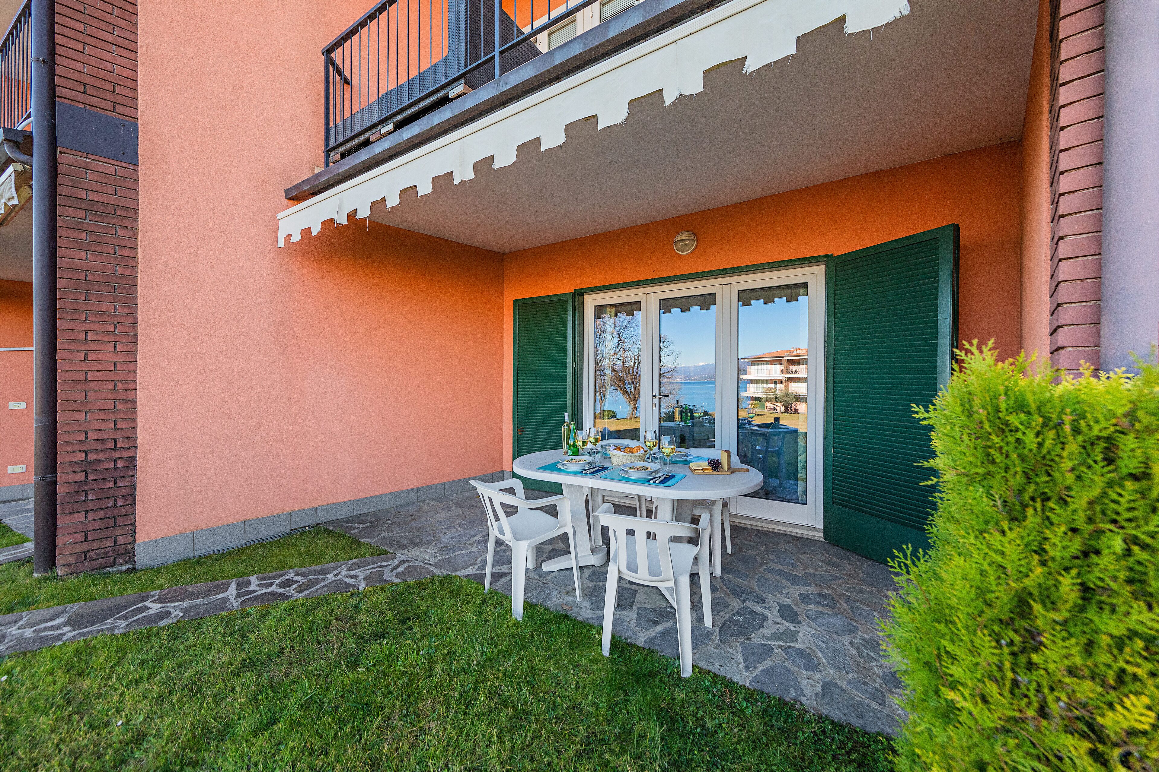 A patio with a table and chairs, a small garden, and a view of the sea.
