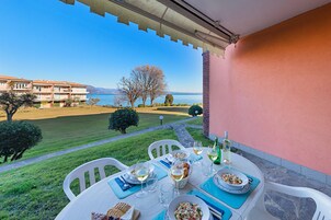 Eine Terrasse mit Essplatz, mit Blick auf ein Gewässer und ein entferntes Gebirge.