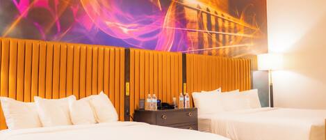 A hotel room with two beds, a nightstand, a lamp, and a vibrant abstract mural on the wall.