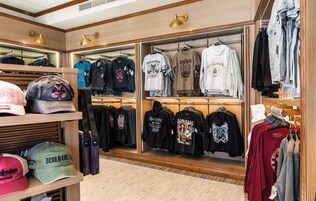 A clothing store with wooden shelves and racks displaying various t-shirts and hoodies.