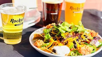 A plate of nachos with various toppings and three glasses of beer.