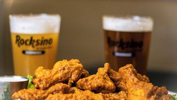 A plate of fried chicken with two glasses of beer labeled "RockSino" in the background.