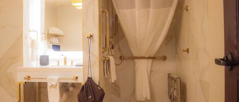 Une salle de bain avec un mur en marbre, une douche avec une porte en verre et un porte-serviettes.
