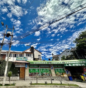 A building with a sign for 'Hostal Taxo Yura' and another sign for 'Viveres y Frutas Legumbres La Foch'. - Pedro Gualan (Quito)