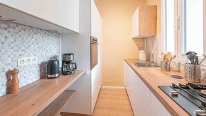 Uma cozinha moderna com bancada de madeira, cafeteira, fogão e painel de azulejos.
