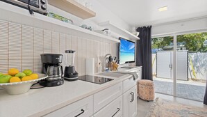A modern kitchen with a coffee maker, fruit bowl, and a TV displaying a scenic view.
