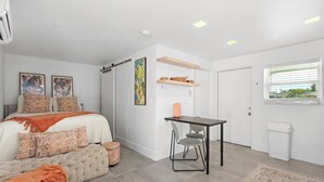 A modern bedroom with a bed, bedside tables, a desk, and a window.
