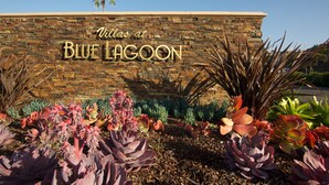 Un muro de piedra con el texto "Villas at Blue Lagoon" y diversos cactus en primer plano.