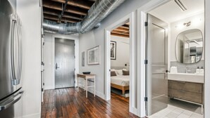 A modern kitchen with stainless steel appliances, a wooden floor, and a visible ductwork on the ceiling. - Live the Jazz Life: Modern 4BR Condo in NOLA (New Orleans)
