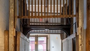 A narrow hallway with wooden doors and a metal gate at the end.