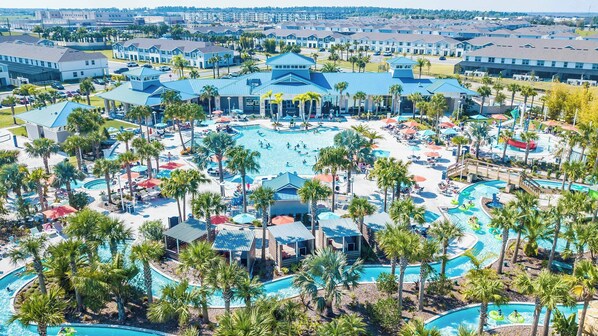 Un resort con varias piscinas, palmeras y un edificio central con techo azul.