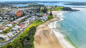 Vista aérea de una zona residencial costera con casas, una playa y una bahía.