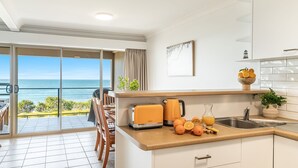 Eine moderne Küche mit Meerblick, ausgestattet mit einem Toaster, einem Wasserkocher und frischen Orangen auf der Arbeitsplatte.