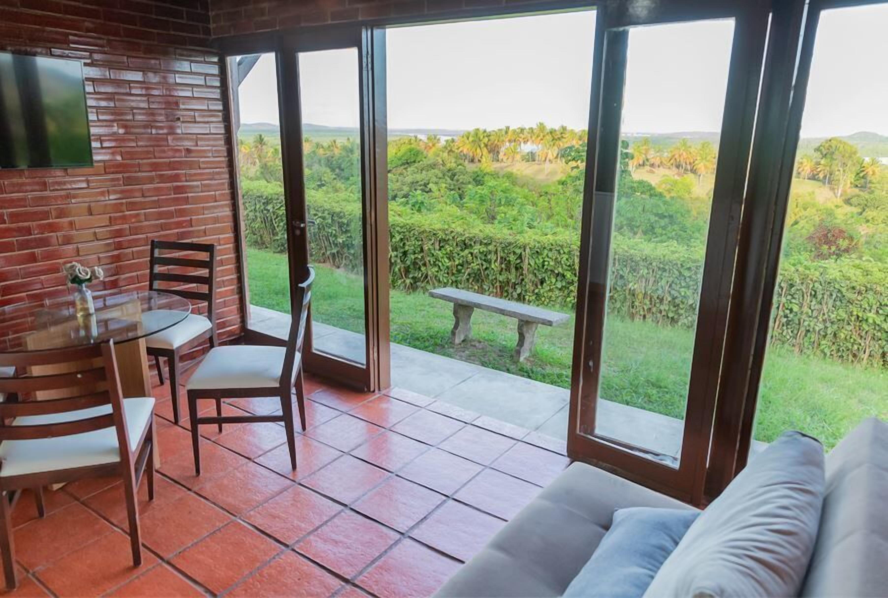 Uma varanda com porta de vidro, uma mesa com cadeiras e um sofá.