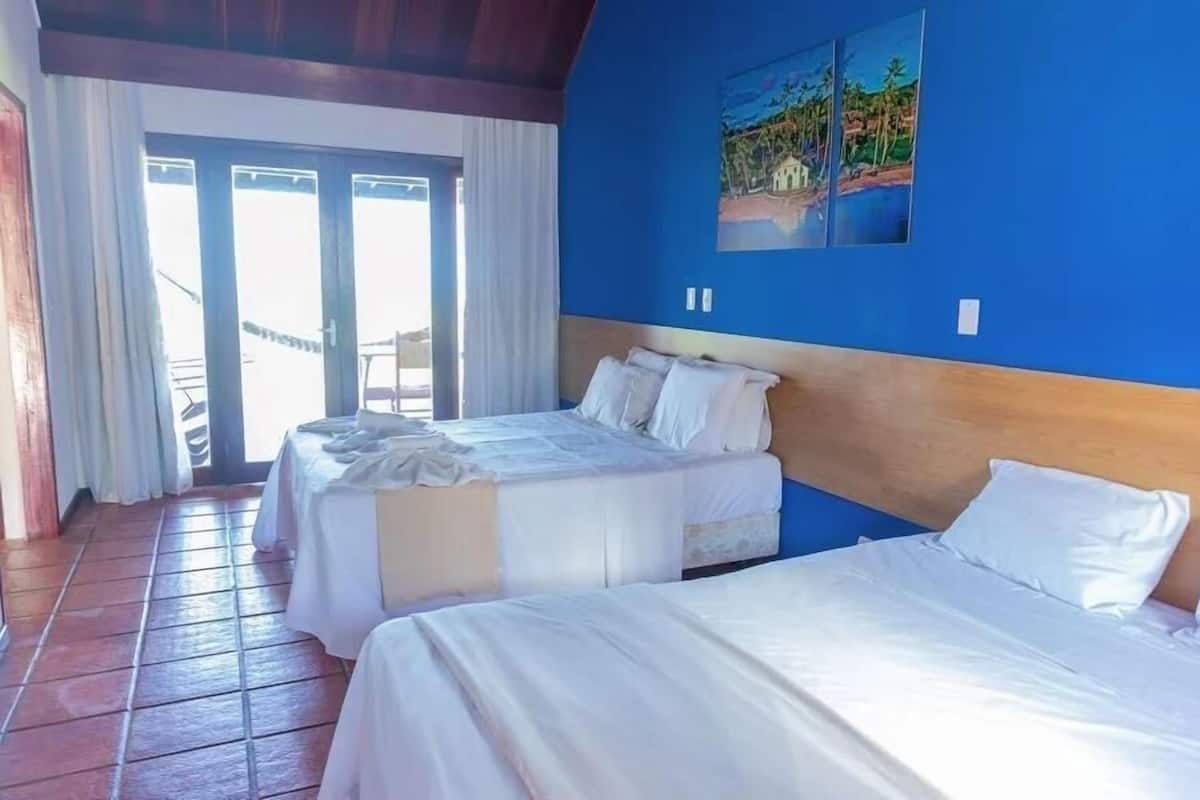 Une chambre d’hôtel avec deux lits, un plafond en bois et un tableau au mur.