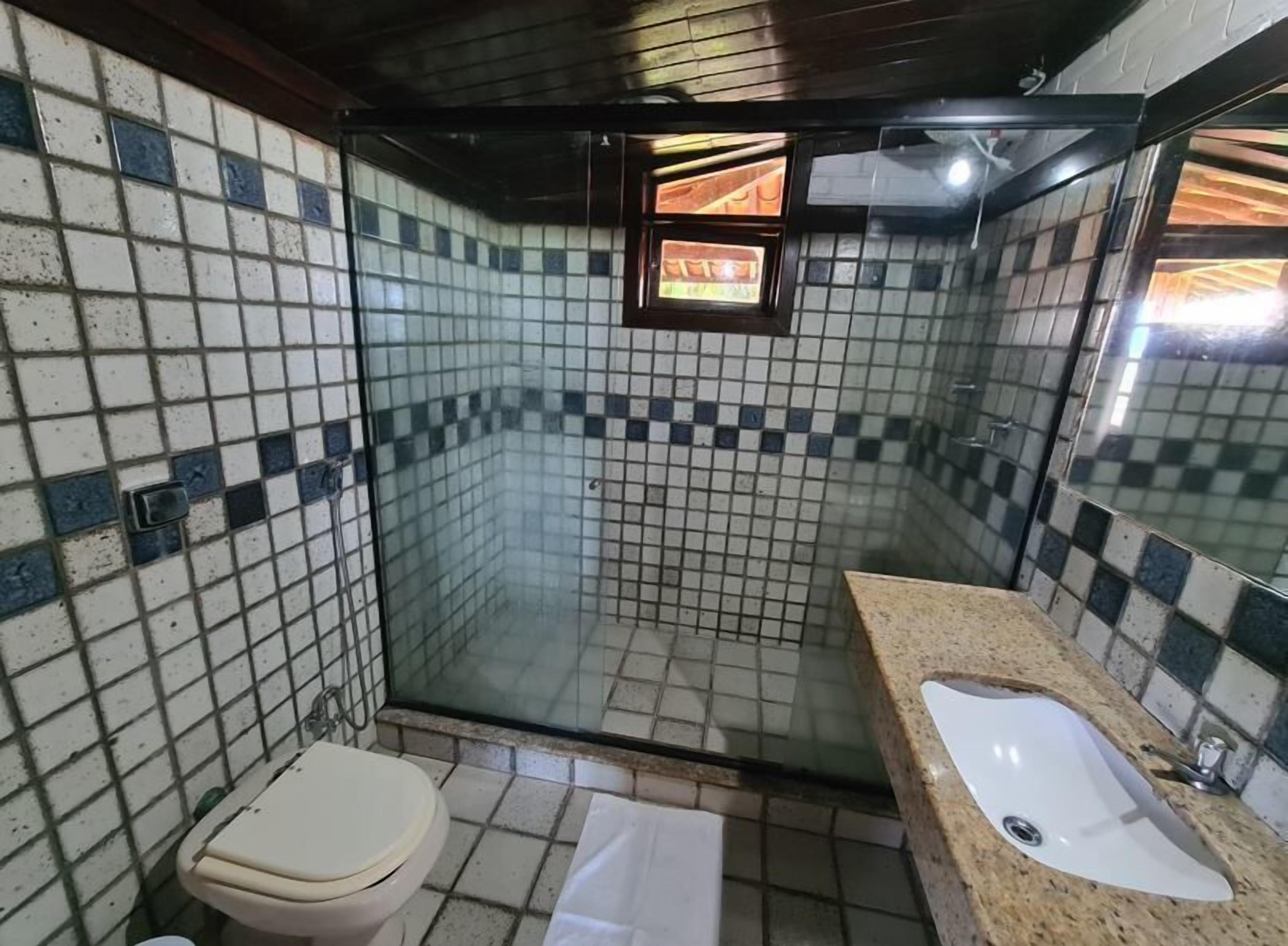 Un bagno piccolo rivestito di piastrelle, con doccia, wc e lavandino.