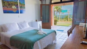 Une chambre d’hôtel avec un lit, une table en bois et une vue sur un paysage tropical.