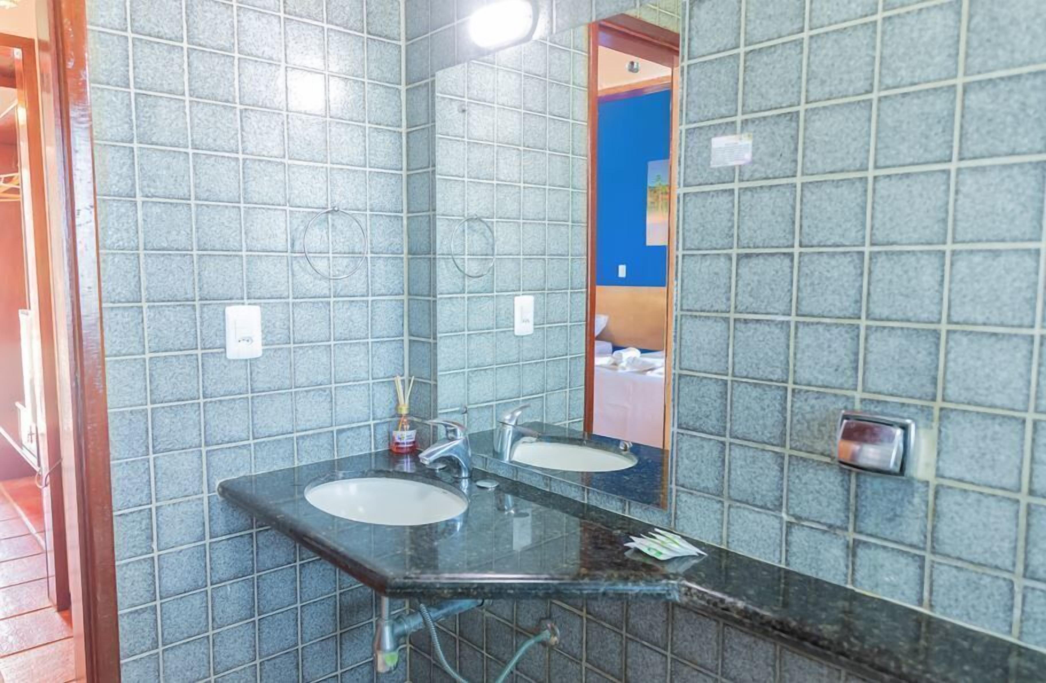 A bathroom with two sinks, a mirror, and tiled walls.