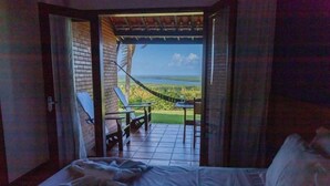 Une chambre avec un lit, une vue sur un hamac et une table avec des chaises à l’extérieur.