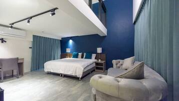 Een moderne hotelkamer met een bed, bureau en zithoek.
