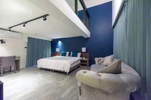 Une chambre d’hôtel moderne équipée d’un lit, d’un bureau et d’un coin salon.
