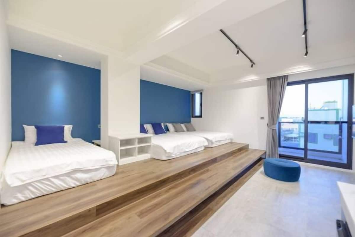 A modern hotel room with a large bed, a smaller bed, and a seating area.
