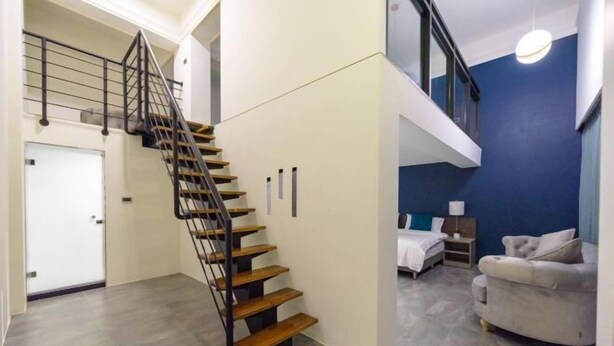 A modern interior with a staircase, a bed, a sofa, and a door. - Daytime (Penghu)