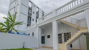 A modern building with a covered outdoor area, a staircase, and a well-maintained lawn. - Daytime (Penghu)