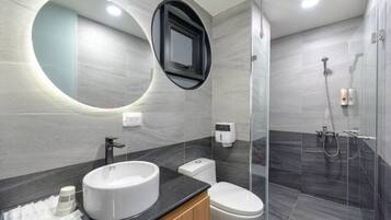 Een moderne badkamer met een ronde spiegel, twee wastafels, een toilet en een douchecabine met glazen wanden.