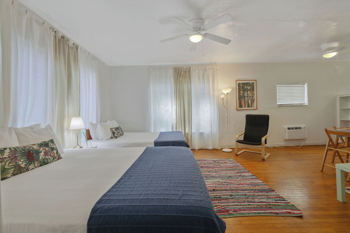 Een hotelkamer met een bed, een stoel, een bureau en een plafondventilator.