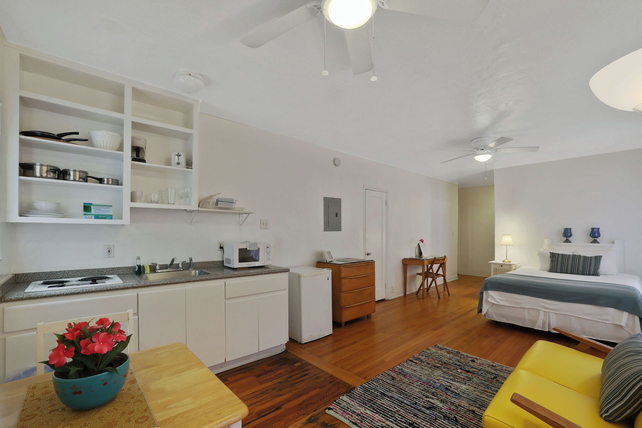A compact living space with a kitchenette, a dining area, a bed, and a small seating area.