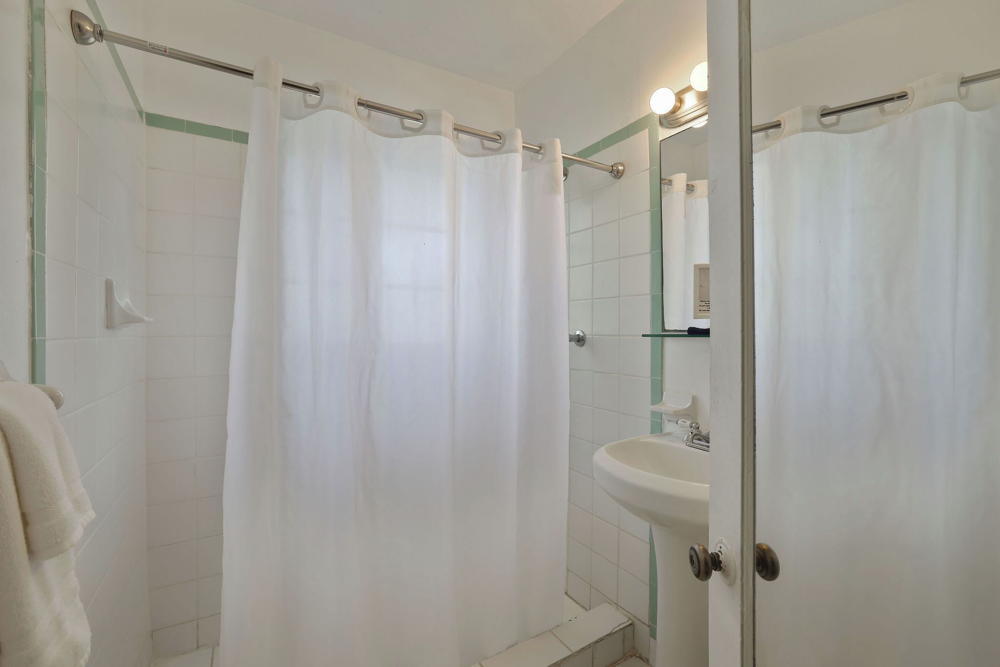 A bathroom with a shower curtain, a sink, and a mirror.