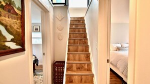 Un couloir étroit avec un escalier en bois menant à une chambre.